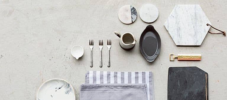 Minimal bir sofrada yemek tabağı, peynir tahtası, sunum tabağı ve peçeteler