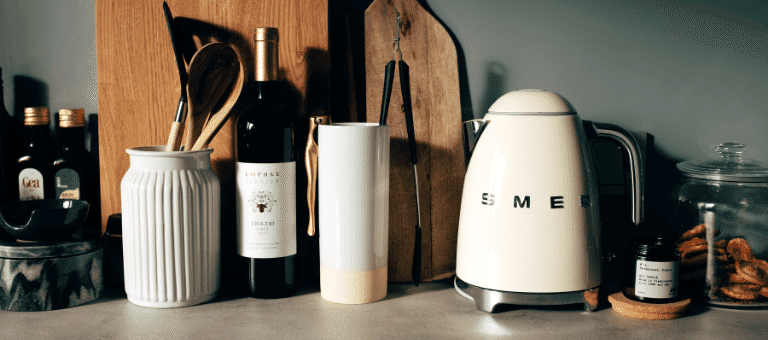 Bir mutfak rafında seramik aksesuarlar, cam kavanozlar ve smeg kettle